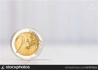 Two euros coin on white wood background. With copy-space for text
