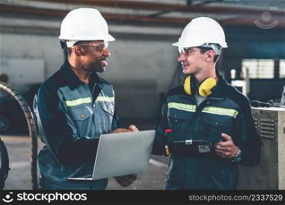 Two factory workers using adept machine equipment in a workshop . Industry manufacturing and engineering technology concept .. Two factory workers using adept machine equipment in a workshop