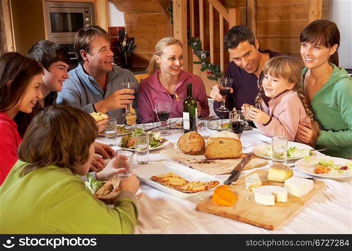 Two Familes Enjoying Meal In Alpine Chalet Together