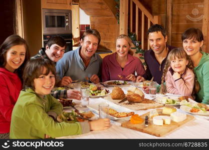 Two Familes Enjoying Meal In Alpine Chalet Together