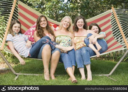 Two families sitting in a hammock and smiling