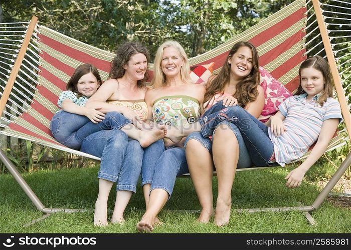 Two families sitting in a hammock and smiling