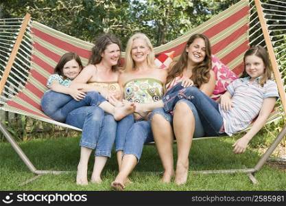 Two families sitting in a hammock and smiling