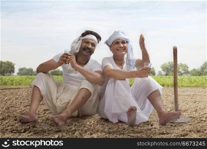 Two farmers sitting in field drinking tea