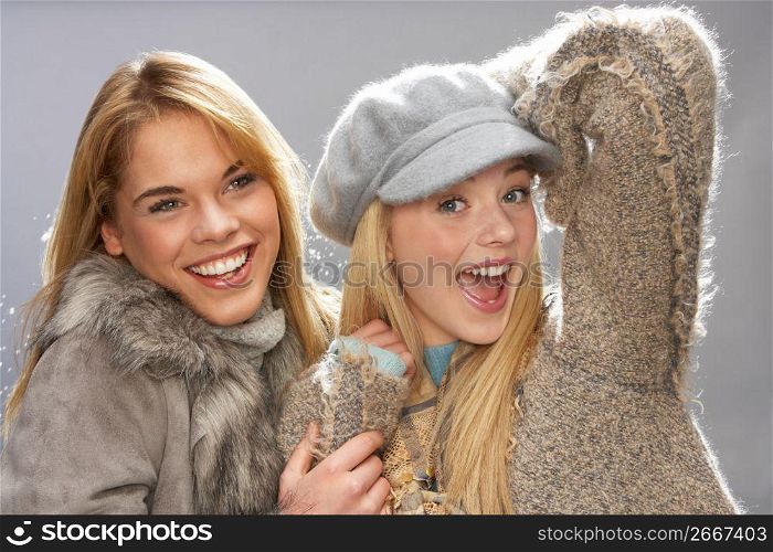 Two Fashionable Teenage Girls Wearing Cap And Knitwear In Studio