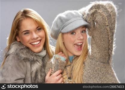 Two Fashionable Teenage Girls Wearing Cap And Knitwear In Studio