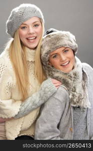 Two Fashionable Teenage Girls Wearing Cap And Knitwear In Studio In Front Of Christmas Tree