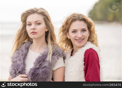 Two fashionable women wearing stylish outfits during warm autumnal weather spending their free time outdoor. Two fashionable women outdoor