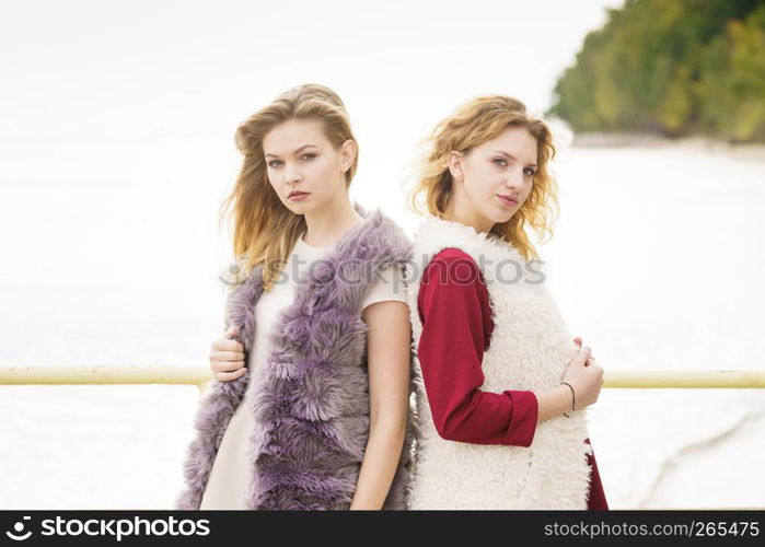 Two fashionable women wearing stylish outfits during warm autumnal weather spending their free time outdoor. Two fashionable women outdoor