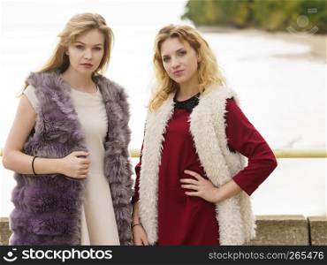 Two fashionable women wearing stylish outfits during warm autumnal weather spending their free time outdoor. Two fashionable women outdoor