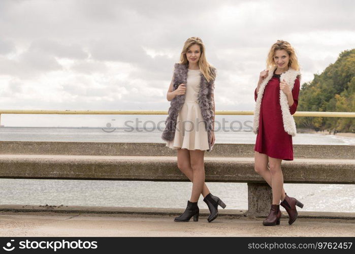 Two fashionable women wearing stylish outfits during warm autumnal weather spending their free time outdoor. Two fashionable women outdoor