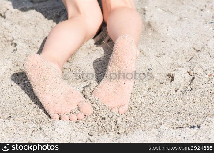 Two feet of a boy in sand at at beach. Two feet of a boy in sand at at beach relaxing