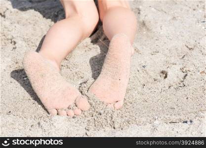Two feet of a boy in sand at at beach. Two feet of a boy in sand at at beach relaxing