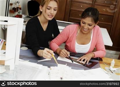 Two female architects drawing a blueprint and smiling
