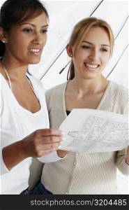 Two female architects holding a blueprint and smiling