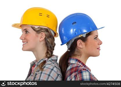 Two female builders standing back to back