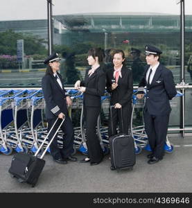 Two female cabin crews standing with two pilots at an airport