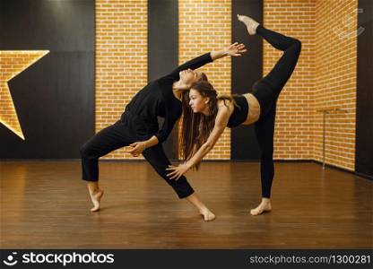 Two female contemporary dance performers in studio. Dancers training in class, modern elegance dancing, stretching exercise. Two female contemporary dance performers