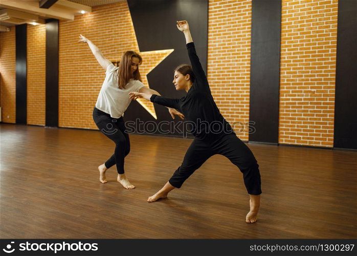 Two female contemporary dance performers poses in studio. Dancers training in class, modern elegance dancing, stretching exercise. Two contemporary dance performers poses in studio