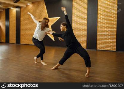 Two female contemporary dance performers poses in studio. Dancers training in class, modern elegance dancing, stretching exercise. Two contemporary dance performers poses in studio