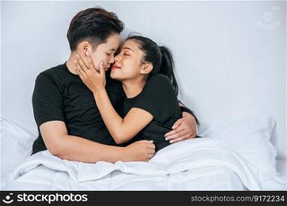 Two female couples cuddled together in bed.