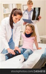 Two female doctors examine x-ray broken leg little girl
