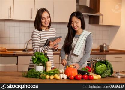 Two female friends are cooking together at home