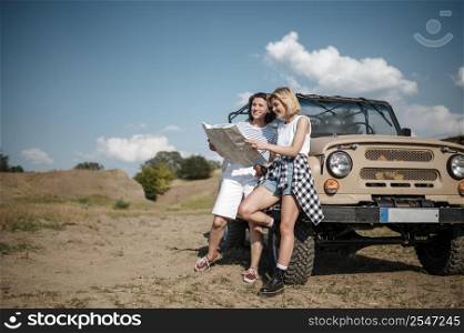 two female friends checking map while traveling by car