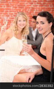 Two female friends drinking champagne in restaurant