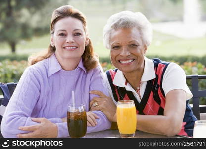 Two Female Friends Enjoying A Beverage By A Golf Course