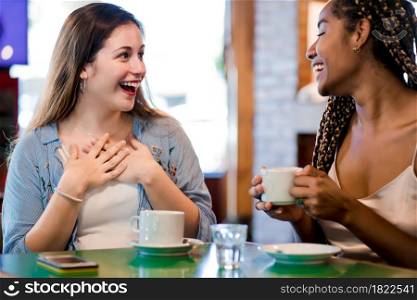 Two female friends enjoying time together while drinking a cup of coffee at a coffee shop. Friends concept.