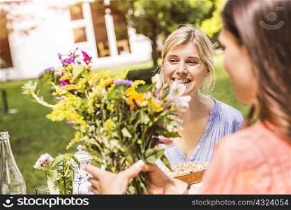 Two female friends in garden, looking at bunch of flowers