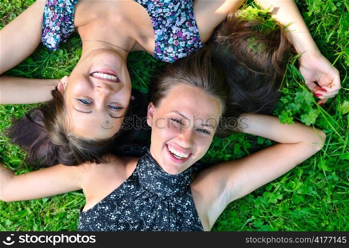 two female friends is lying on grass and laughing