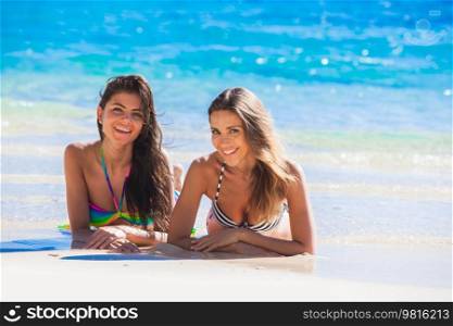 Two female friends laying on the sand of tropical beach. Two female friends laying on beach