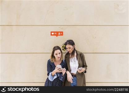 two female friends looking likes comments notification cellphone