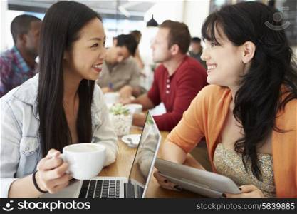 Two Female Friends Meeting In Busy Coffee Shop