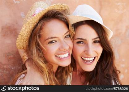 Two Female Friends On Holiday Together Posing By Wall