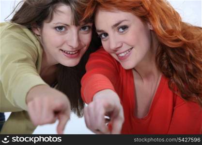 Two female friends pointing at the camera.
