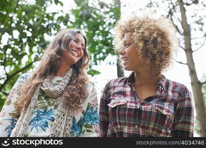 Two female friends walking and talking in forest