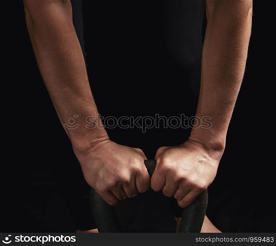 two female hands hold the handle of an iron kettlebell, low key