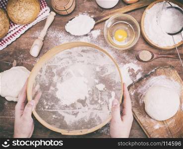 two female hands holding an old wooden sieve for flour above the kitchen table, vintage tonin