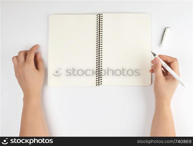 two female hands holding open notepad with clean sheets on a white background, top view