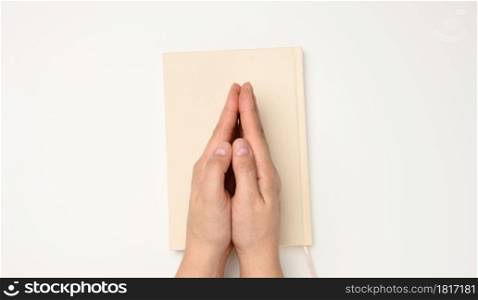 two female hands in a prayer pose on a white background, top view