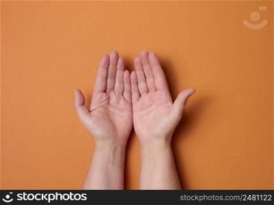 two female hands on a brown background. Empty palms open, top view