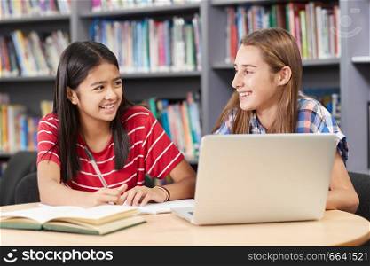 Two Female High School Students Working At Laptop In Library