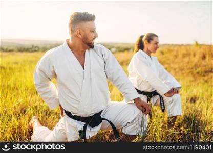 Two female karate with male instructor on training in summer field. Martial art workout outdoor, technique practice. Two female karate with male instructor on training