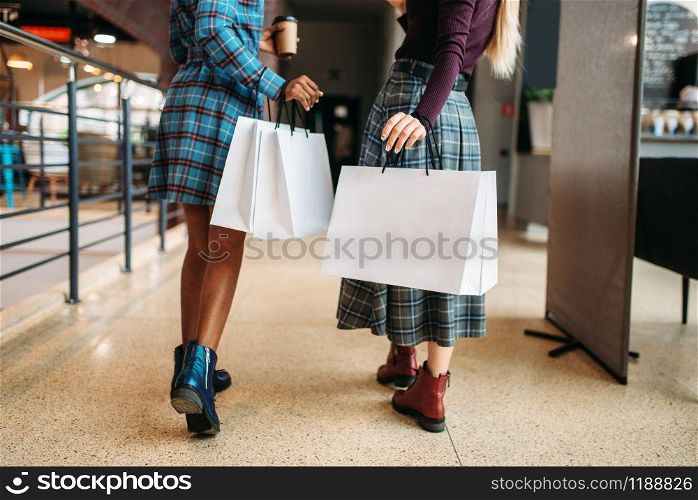 Two female persons with shopping bags in shop. Shopaholics in clothing store, consumerism lifestyle, fashion