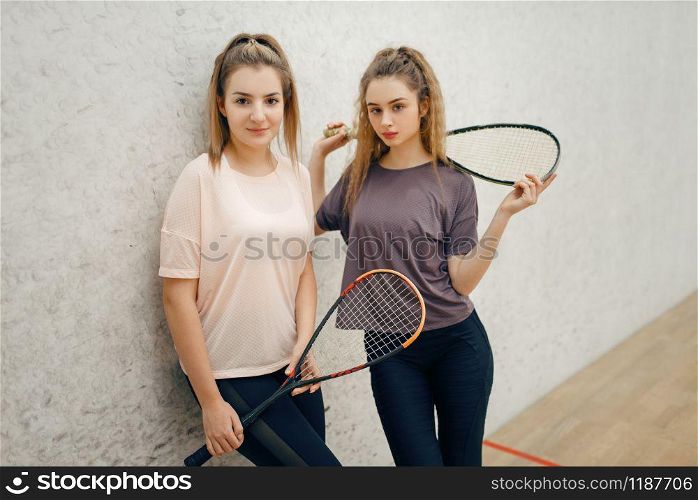 Two female players poses with squash rackets on court. Girls on game training, active sport hobby, fitness workout for healthy lifestyle. Two female players poses with squash rackets