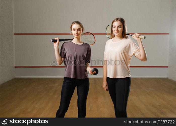 Two female players shows squash rackets. Girls on training, active sport hobby, fitness workout for healthy lifestyle. Two female players shows squash rackets