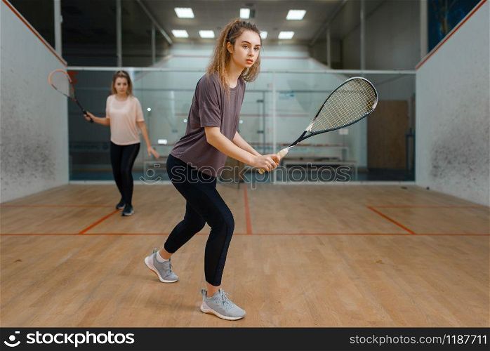 Two female players with rackets, squash game on court. Girls on training, active sport hobby, fitness workout for healthy lifestyle. Two female players with rackets, squash game